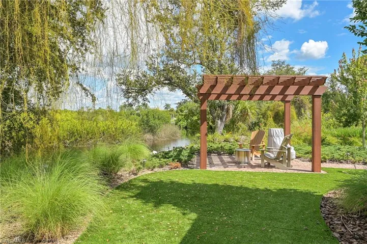 Gazebo with seating amid manicured grounds and water views, complemented by maintenance free turf for effortless outdoor enjoyment