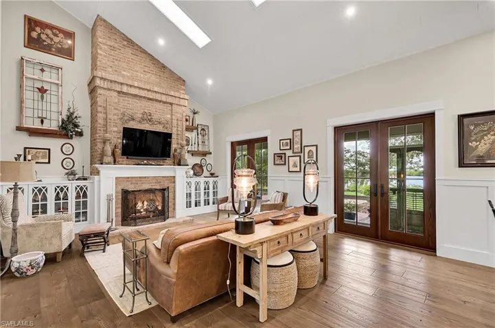 Statement brick gas fireplace, bespoke built-in cabinetry, and vaulted ceilings accented by skylights.  Multiple French doors open to the outdoors, enhancing the home's seamless indoor-outdoor flow