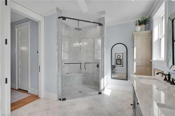 Spacious glass enclosed walk-in shower with elegant tile work, designer features, and abundant natural light