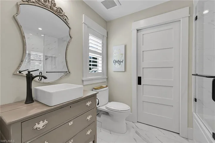 Stylish bathroom featuring a custom vanity with vessel sink, designer mirror, and modern features.  Door opens into full walk-in closet