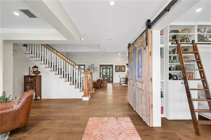 Striking entry foyer featuring custom brick inlay flooring, wide-plank hardwood floors, and an open staircase.  The space leads seamlessly into the great room with soaring vaulted ceilings and skylights