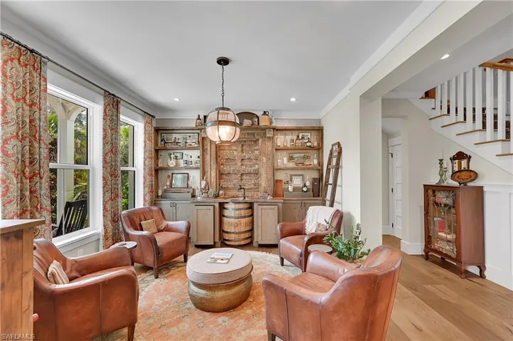 Inviting den designed for entertaining, complete with custom bar, whiskey barrel sink, integrated wine storage, beverage refrigerator, and hidden tv behind handcrafted wood doors