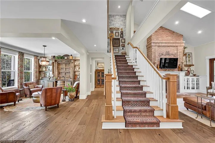 View from the kitchen into the great room and den, highlighting an elegant staircase, and thoughtfully curated living spaces designed for both comfort and entertaining