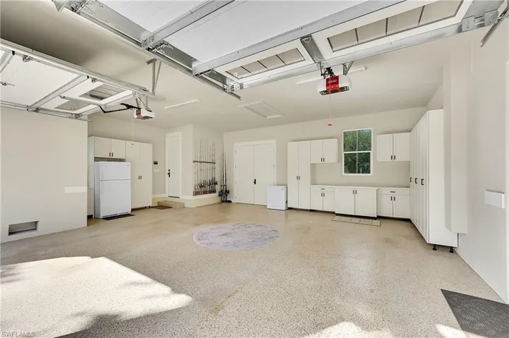 Immaculate garage with epoxy flooring, extensive built-in cabinetry, and a dedicated work area.  Clean, organized, and ideal for storage, hobbies, or multiple vehicles