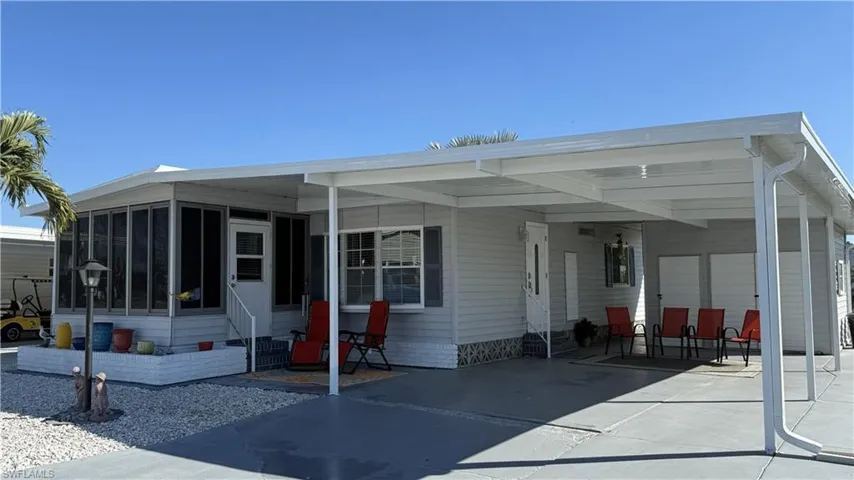 View of front of property with a sunroom, an attached carport, entry steps, and driveway