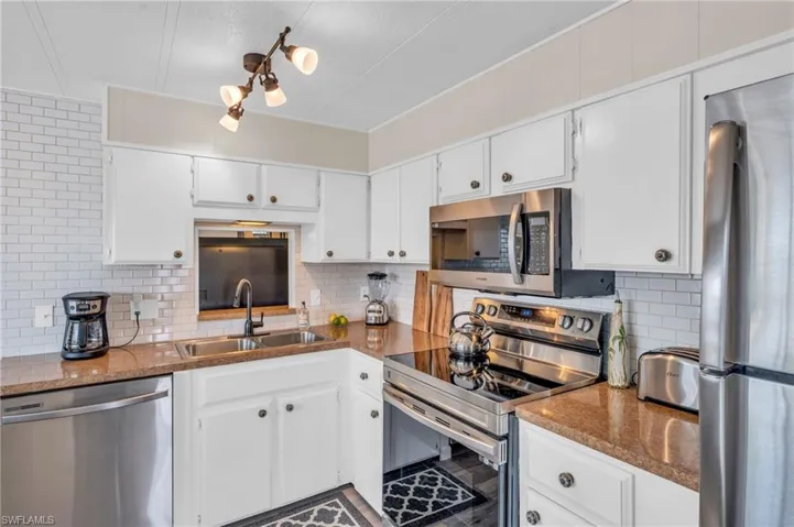 Kitchen featuring laminate counters, white cabinetry, sink, and stainless steel appliances