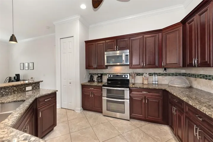 Kitchen featuring stainless steel appliances, ornamental molding, decorative backsplash, ceiling fan, and pendant lighting