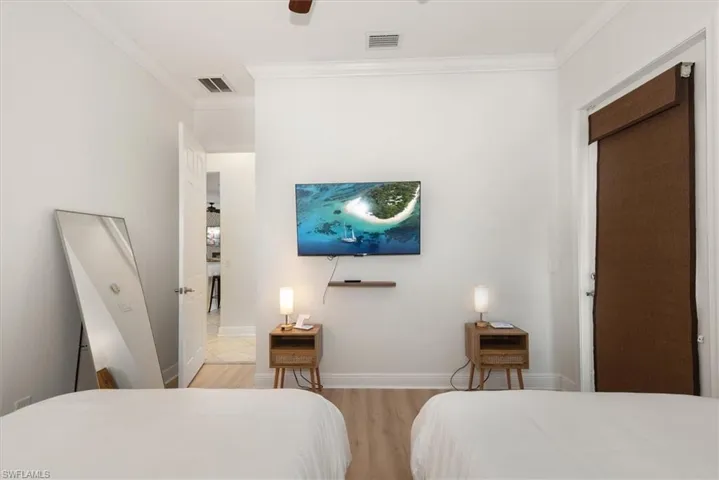 Bedroom with crown molding, light wood finished floors, baseboards, and ceiling fan