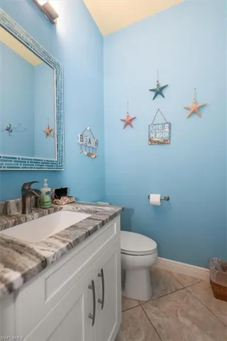 Half bath featuring vanity, tile patterned flooring, toilet, and baseboards