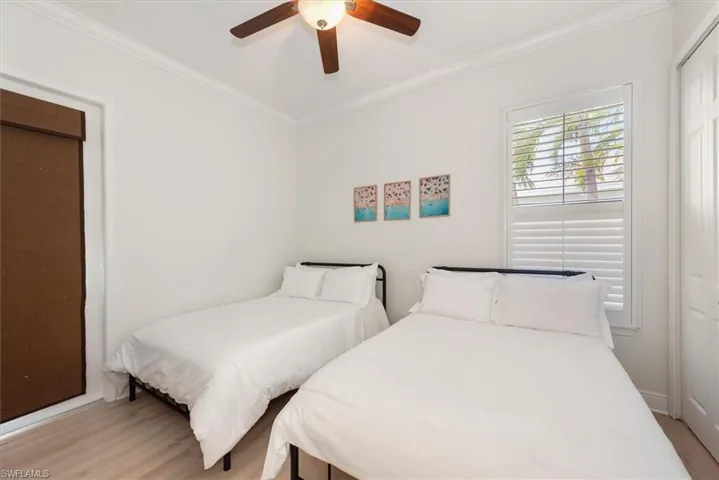 Bedroom featuring light wood-style floors, crown molding, and ceiling fan