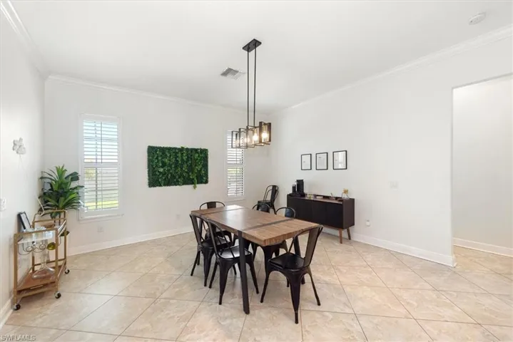 Dining room with ornamental molding, light tile patterned floors, baseboards, and a chandelier