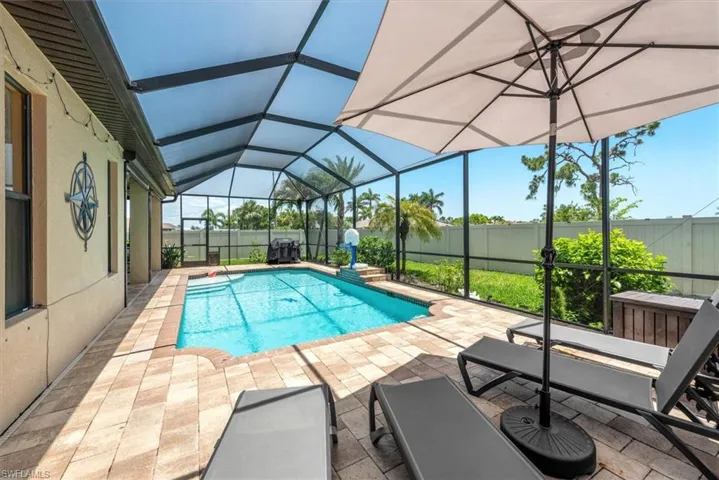 View of pool featuring a patio, glass enclosure, and a fenced backyard
