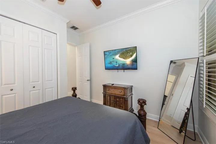Bedroom featuring light wood-type flooring, crown molding, a closet, baseboards, and a ceiling fan