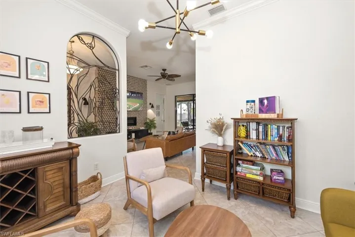 Sitting room with crown molding, a chandelier, a fireplace, tile patterned floors, and a ceiling fan