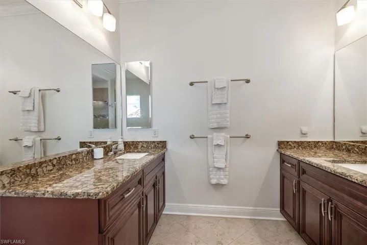 Full bathroom with two vanities, baseboards, and a shower