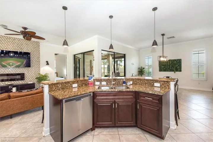 Kitchen with dishwasher, a sink, open floor plan, light tile patterned flooring, and crown molding