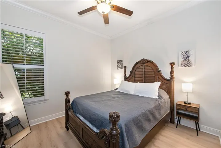 Bedroom with light wood-type flooring, baseboards, ornamental molding, and a ceiling fan