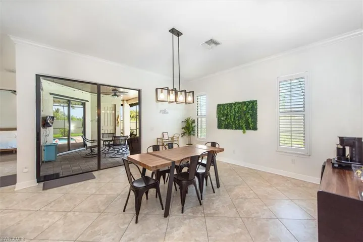 Dining space with crown molding, light tile patterned flooring, ceiling fan, and baseboards