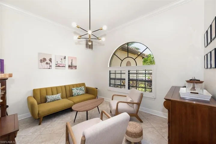 Living area with a chandelier, ornamental molding, baseboards, and light tile patterned floors
