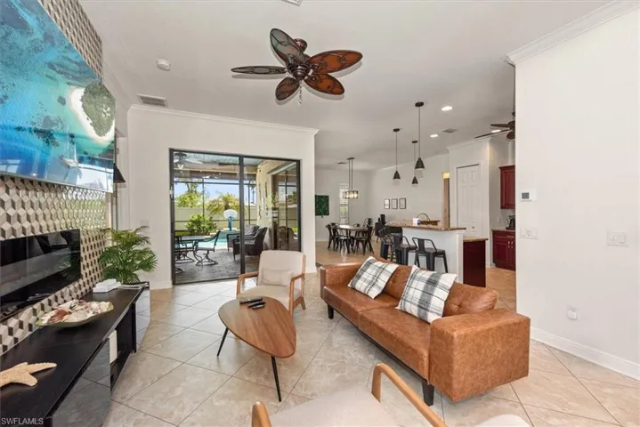 Living area featuring a ceiling fan, ornamental molding, recessed lighting, light tile patterned floors, and baseboards