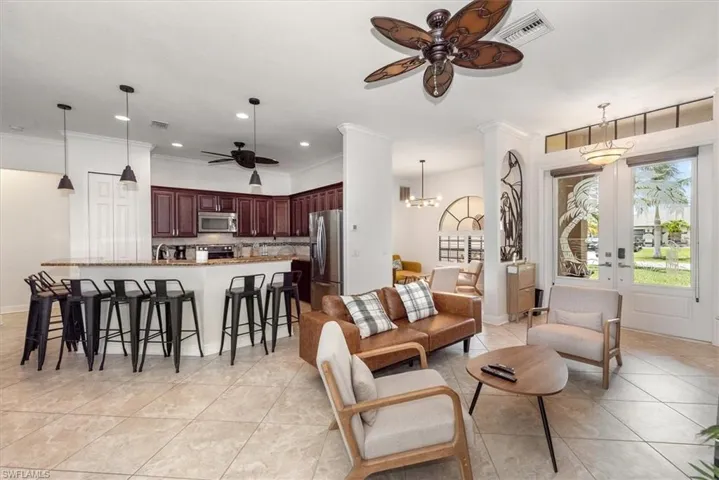 Living room featuring a ceiling fan, light tile patterned floors, crown molding, recessed lighting, and a chandelier
