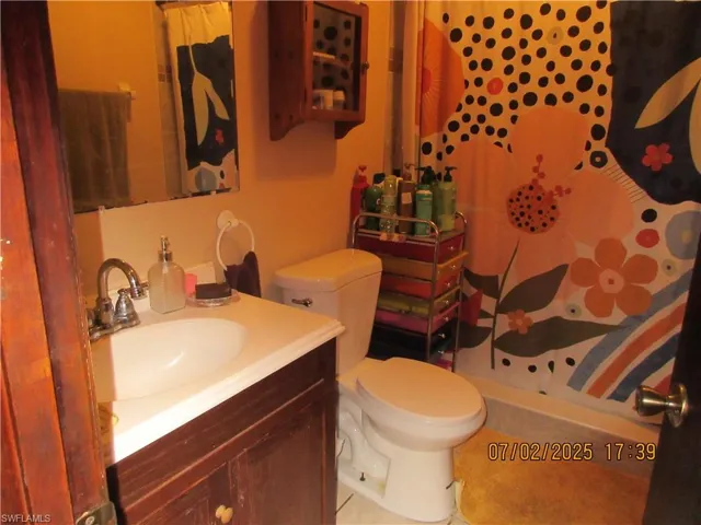 Full bath with curtained shower, vanity, and tile patterned flooring