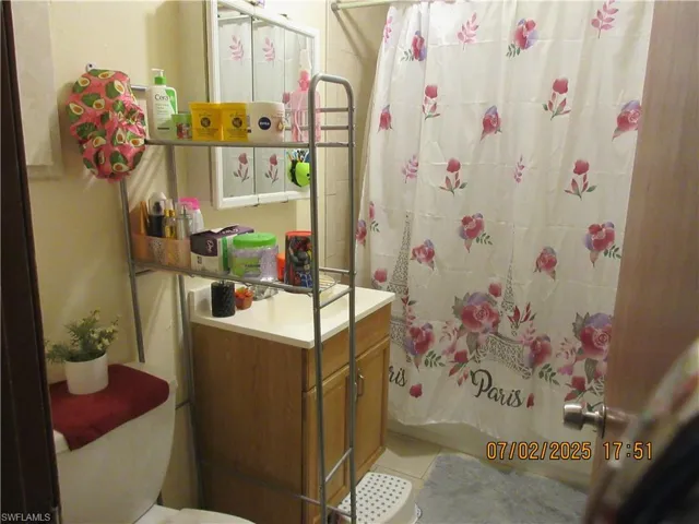 Full bathroom with a shower with shower curtain, vanity, and tile patterned flooring