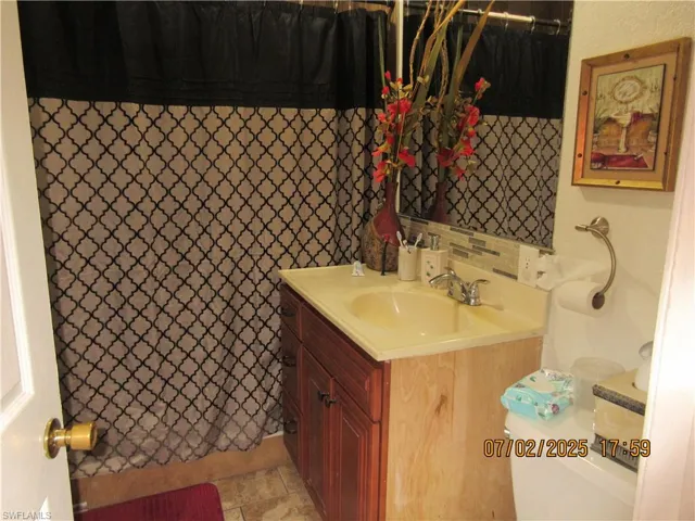 Full bath featuring vanity, a shower with shower curtain, and stone finish floors