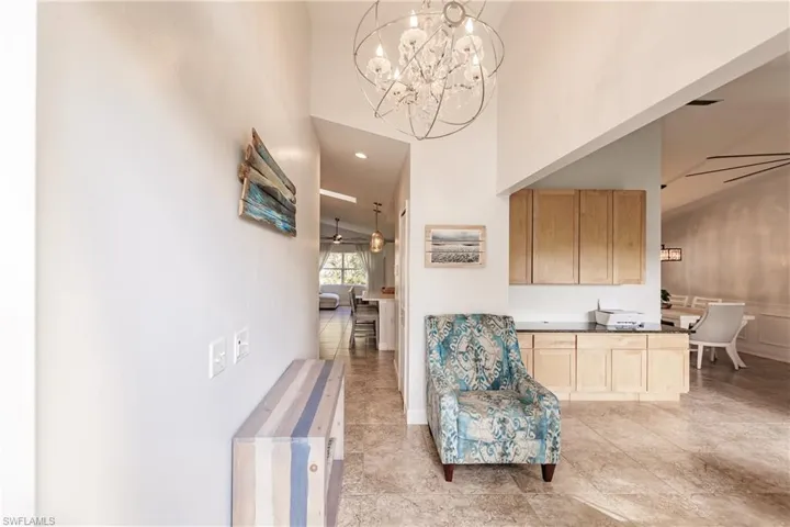 Living area featuring high vaulted ceiling and ceiling fan with notable chandelier
