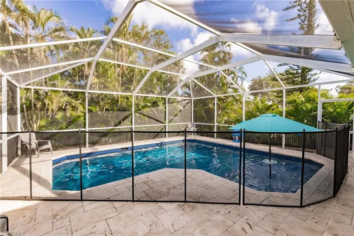 View of swimming pool with screen enclosure and a patio