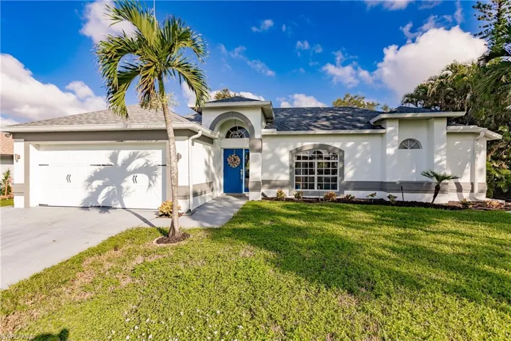 View of front facade featuring a front yard and a garage