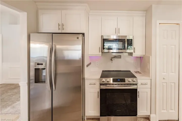 Kitchen featuring white cabinets and stainless steel appliances and pot filler