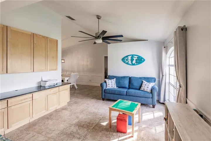 Den featuring vaulted ceiling and ceiling fan