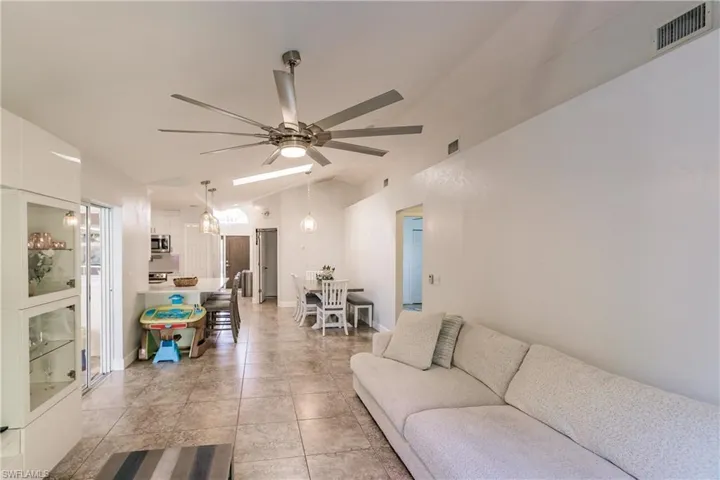 Living room with vaulted ceiling, ceiling fan, and light tile patterned floors