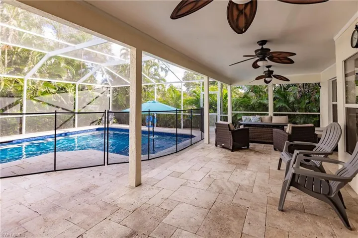 View of swimming pool featuring an outdoor living space, ceiling fan, glass enclosure, and a patio