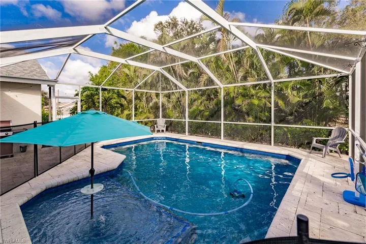 View of swimming pool with screen enclosure and a patio area