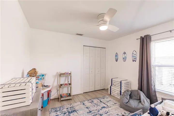 Bedroom with ceiling fan, a closet, and light wood-type flooring
