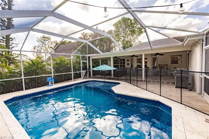 View of swimming pool featuring screen enclosure, ceiling fan, and a patio