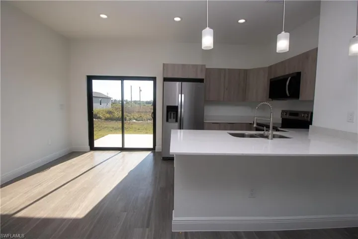 Kitchen featuring sink, light brown cabinets, appliances with stainless steel finishes, and hanging light fixtures