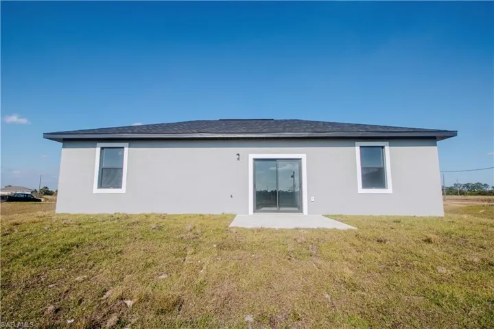 Back of house featuring a lawn and a patio