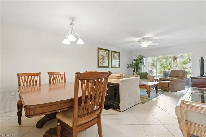 Dining room with light tile patterned flooring and ceiling fan with notable chandelier