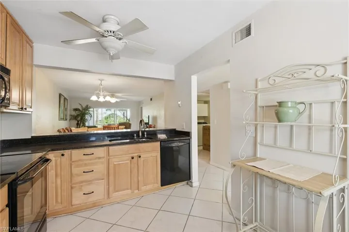 Kitchen with a sink, visible vents, ceiling fan with notable chandelier, black appliances, and light tile patterned floors