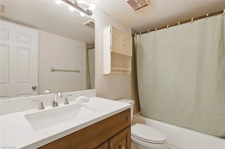 Bathroom featuring shower / bath combo, visible vents, vanity, and toilet
