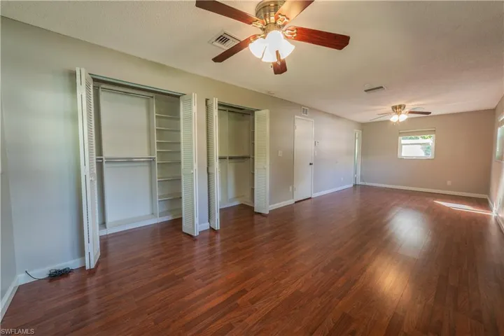 Unfurnished bedroom featuring hardwood / wood-style flooring, multiple closets, a textured ceiling, and ceiling fan