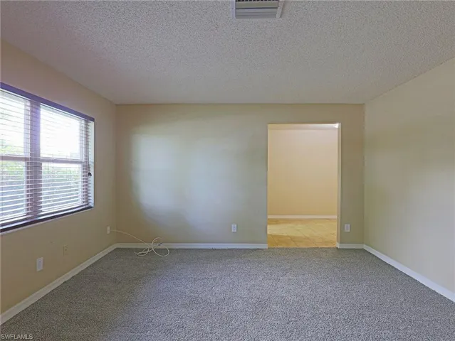 Carpeted spare room featuring a textured ceiling