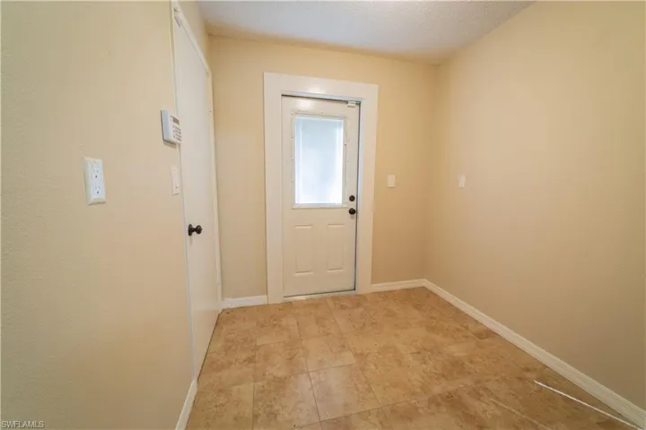 Doorway with light tile patterned floors and a textured ceiling