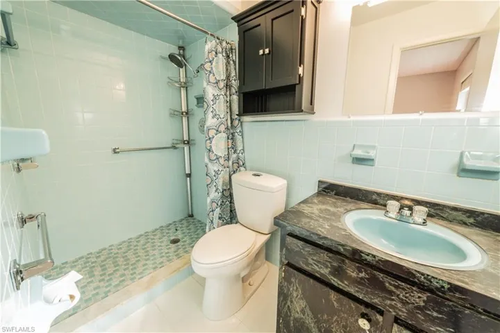 Bathroom with tile walls, tasteful backsplash, vanity, and toilet