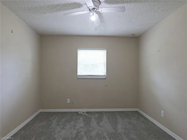 Carpeted spare room featuring ceiling fan and a textured ceiling
