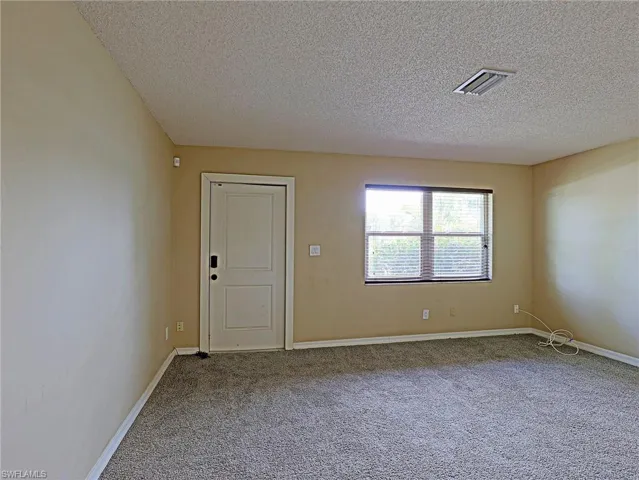 Empty room featuring carpet flooring and a textured ceiling