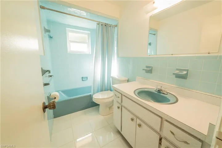 Full bathroom with backsplash, toilet, vanity, tile walls, and shower / tub combo